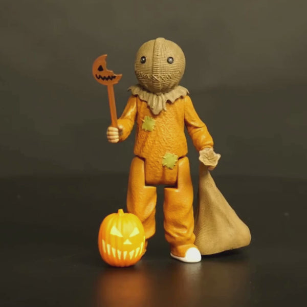 360 degree video of Sam figure. Head is a stitched burlap sack, Button eyes, stitched mouth, rope tied at neck. wearing orange footy pajamas, brown fingerless gloves. Holding bitten jack o' lantern lollipop in right hand, burlap sack in left hand. Orange and yellow Jack o' lantern next to right foot